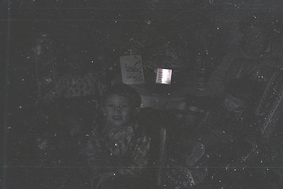 Vintage black-and-white photo of a child holding a lantern with Cyrillic script, likely Bulgarian. Indoor setting with rough ...