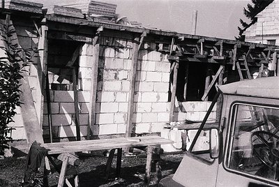 Damaged concrete structure with exposed scaffolding and wooden supports, likely post-earthquake or collapse. Partial view of ...