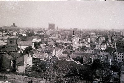 Black-and-white aerial view of a European cityscape, likely early-to-mid 20th century. Dense cluster of low-rise buildings wi...