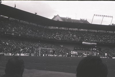 Vintage black-and-white stadium shot showing packed stands with dense crowds, likely during a 1960s–1970s European football m...
