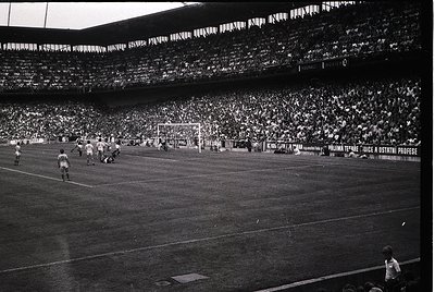 Vintage black-and-white stadium shot featuring a packed arena with players mid-match. Visible signage reads *"Palma Terme: Ju...