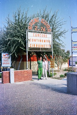 Vintage airport departure board displaying flights to Rome Ciampino (AZ 760), Concord, Continental, and Gardimetto. Two passe...