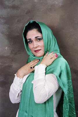 Portrait of a woman in traditional attire, likely from the Middle East or South Asia. She wears a bright green headscarf and ...