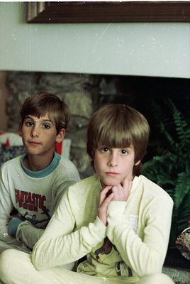 Two boys pose indoors, likely mid-1980s–90s, in matching light-colored sweatshirts with graphic prints. The boy on the right ...