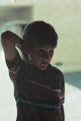 Vintage portrait of a young boy in a striped sweater, captured through a window with spiderweb reflections. Mid-20th century ...