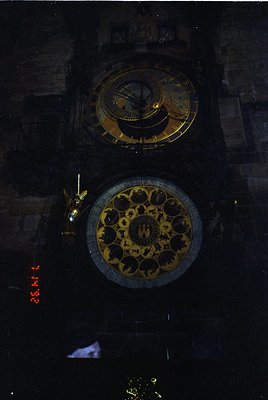 Grand astronomical clock with dual dials—upper hour/date, lower zodiac/calendar—set against Gothic stonework. Likely European...