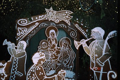 Traditional folk art mural depicting the Nativity scene with stylized figures in white and brown chalk on a dark background. ...