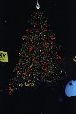 Elaborate metallic Christmas tree display by **ekolamp**, featuring gold-tinted reflective branches and red ornaments. Partia...