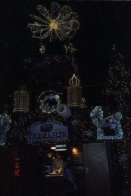 Vibrant illuminated signage featuring a large floral design and decorative lanterns above a café entrance. The Cyrillic text ...