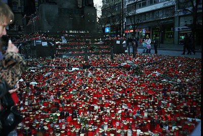 Memorial tribute featuring thousands of red candles and candles in jars arranged in a dense, organized pattern on a city stre...
