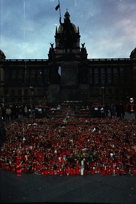 Historic memorial in Prague’s Wenceslas Square featuring a dense arrangement of red candles and floral tributes. The backdrop...