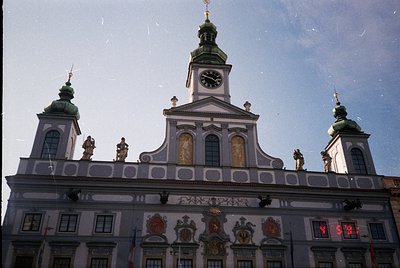 Baroque-style building façade with ornate clock tower, featuring sculpted figures, heraldic crests, and decorative moldings. ...