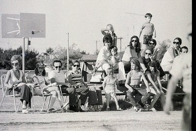 Black-and-white snapshot of a mid-20th-century outdoor gathering, likely 1960s–1970s. Group of ~15 people—adults and children...