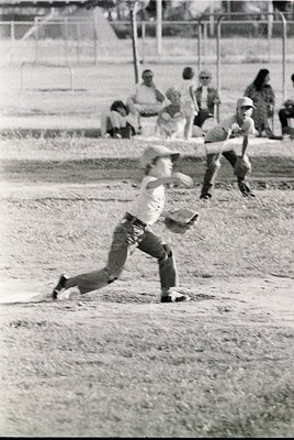 Baseball player mid-slide at home plate, 1960s-70s. Dusty infield, spectators in background. Classic vintage sports action sh...
