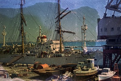 Vintage sepia-toned harbor scene featuring three-masted sailing ships and industrial tugboats. Prominent ship named *"АРХИПЕЛ...