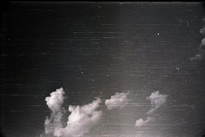 Vintage black-and-white shot of dramatic clouds against a dark, textured wall—likely brick or concrete. The contrast highligh...
