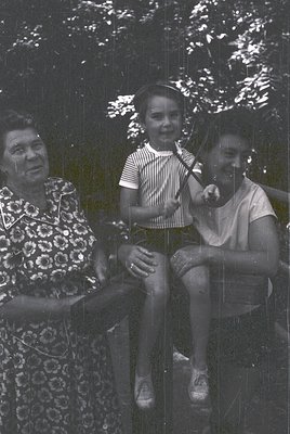 Three generations share a moment on a wooden swing in a lush, shaded park. Elderly woman in floral dress, striped shirt child...