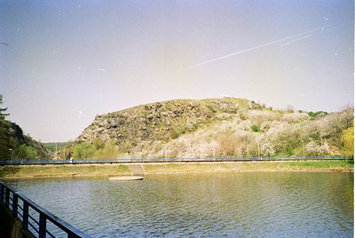 Vintage landscape shot of a serene lake bordered by a wooden walkway. Gentle slope of grassy hill in background with sparse t...