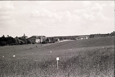 Mid-20th century rural landscape with scattered farmhouses and open fields, likely Eastern Europe. Black-and-white photo capt...
