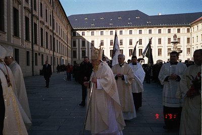 Religious procession in a European courtyard, likely 1970s–1980s. Clergy in ornate liturgical vestments, including a mitre an...