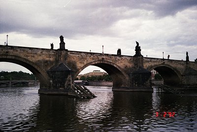 Historic stone bridge spanning a river with Gothic statues atop arches. The Charles Bridge in Prague, Czech Republic, showcas...
