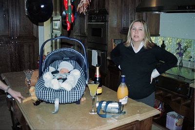 Vintage indoor scene featuring a woman in a 1990s-style sweater posing beside a baby in a checkered carrier on a kitchen coun...