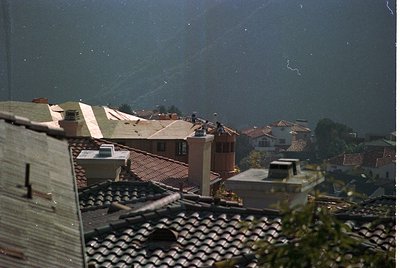 Vintage aerial view of a densely built hillside village with terracotta-tiled roofs and narrow pathways. Likely Mediterranean...