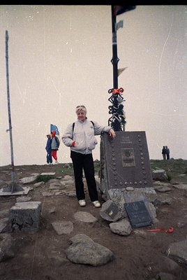 Vintage alpine summit plaque with engraved text ("Vrăciorul" peak, 2508m) and decorative metalwork, set on rocky terrain. Wom...