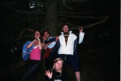 Four individuals pose under a dense forest canopy, likely during a nighttime or low-light hike. Clothing suggests 1990s–2000s...