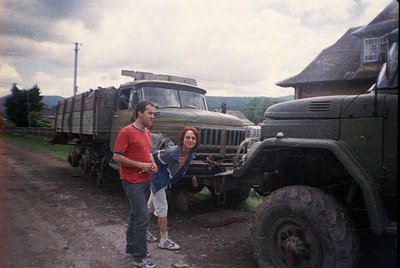 Vintage military truck (likely Soviet-era ZIL-157) parked beside a rural road with two individuals posing. Man in red shirt, ...
