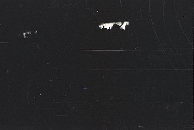 Vintage black-and-white photo of a faint, blurred silhouette resembling a horse’s head against a dark, textured background. L...