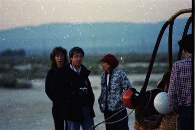 Vintage photo of four individuals on a boat, likely a ferry or fishing vessel, with mountainous coastal backdrop. The scene s...