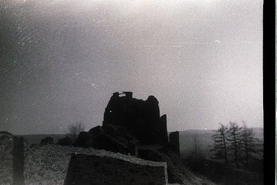 Mid-century black-and-white shot of a ruined stone tower atop rocky terrain, silhouetted against a starry night sky. Minimali...