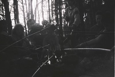 Silhouetted group of people in dense forest, silhouetted against sunlight filtering through trees. Likely mid-20th century ou...