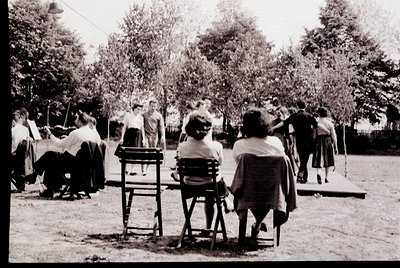 Mid-20th century outdoor gathering in a park setting, featuring women in long skirts and headscarves playing croquet. Wooden ...