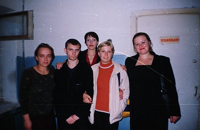 Group portrait of five individuals in a corridor, possibly a public facility. The subjects are dressed in casual attire typic...