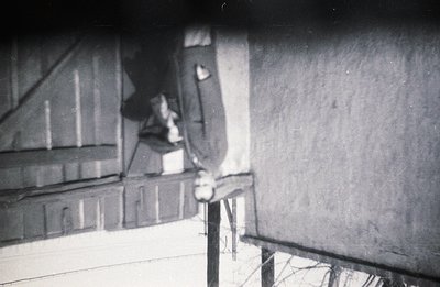Exterior view of a wooden structure, possibly a barn or shed, with a visible birdhouse attached to the wall. The scene has a ...