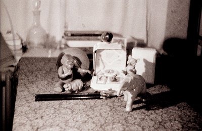 A whimsical scene featuring ceramic figurines: an elephant playing a miniature violin and a cat perched near a vintage portab...