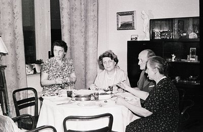 A formal dining scene: four individuals seated around a draped table, enjoying a meal. Notice the detailed cabinet decor and ...