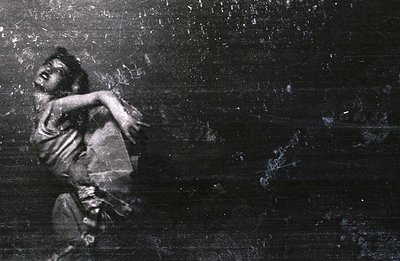 A dancer in mid-motion, captured in a black and white photograph. The subject's arm is extended, creating a dynamic, swirling...