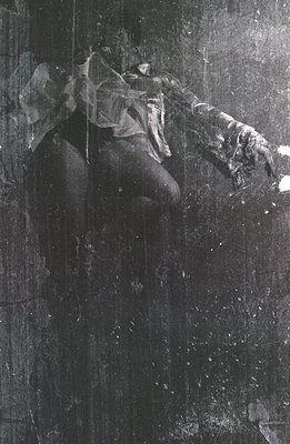 A black and white photograph depicting a person in motion, partially obscured by visible grain and texture. The figure, seemi...