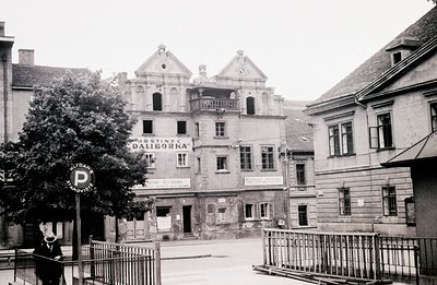 A view of Hotel Daliborka in a European town, showcasing its ornate facade with dormered gables and signage. A man in a coat ...