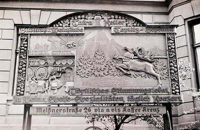 Detailed relief panel showcases a tavern scene with a server presenting a stein and a stag leaping across a mountain landscap...