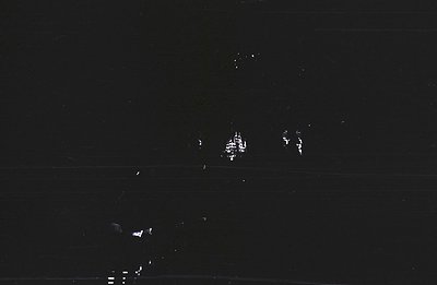 Nighttime photograph featuring illuminated structures against a dark sky, appearing blurred and indistinct. Possibly coastal ...