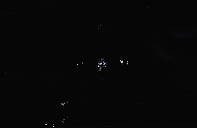 A nighttime architectural view displays a building with lit windows, seemingly a structure with multiple stories. The surroun...