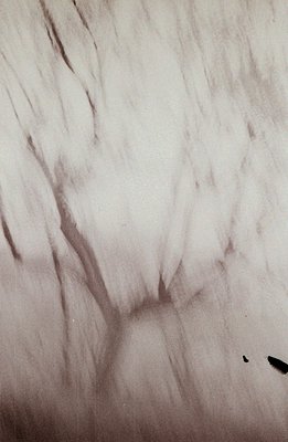 Striking, abstract monochrome image. Textured surface, possibly plaster or stucco, dominates the frame. A central, sculpted o...