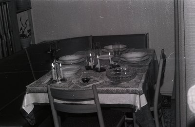 A formal table setting for four is captured in this black and white interior photo. Linen tablecloth, ornate candle holders, ...