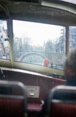 View from a vintage tram, showcasing a canal scene with buildings lining the waterway. Likely a European city, showing a brid...