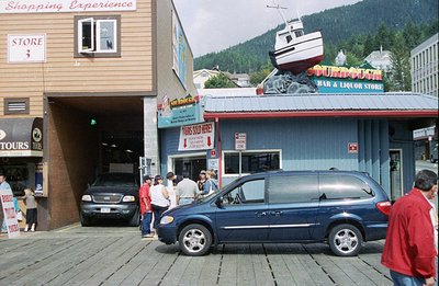 A storefront featuring a stylized fishing boat roof and signage for "Sturgeon Bar & Liquor Store" dominates this scene. Sever...