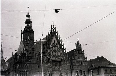 Ornate, historic city hall with a towering clock and detailed, peaked roofline. The building displays Gothic Revival architec...